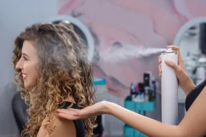 Professional application of heat protectant spray before hot tool styling at Melenas